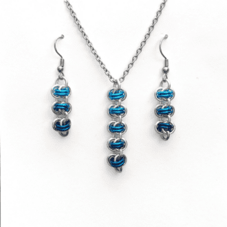 a matching necklace and earring set. The pendant and earrings have been made using silver and graduated shades of blue coloured rings woven into the chainmaille barrel weave pattern.