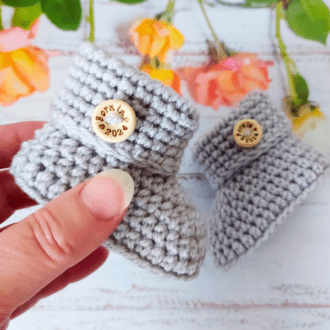 Born in 2024 crochet cuffed baby booties in sizes newborn, 0-3 and 3-6 months they are completed with a wooden button on each bootie that says 'Born in 2024'