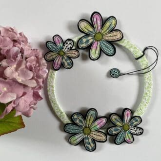 Green fabric wrapped wreath with colourful pink and green daisy flowers