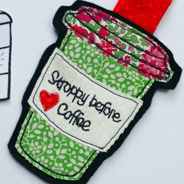 Textile appliqué takeaway coffee cup keyring design with red heart and text saying stroppy before coffee