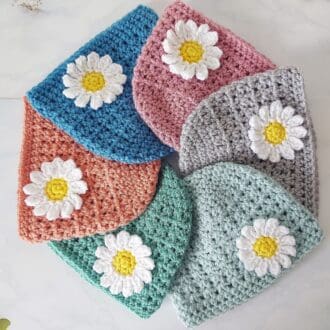 a selection of daisy baby hats that can be ordered in a variety of colours and sizes up to 2 years they are made in one piece and the daisy attached after
