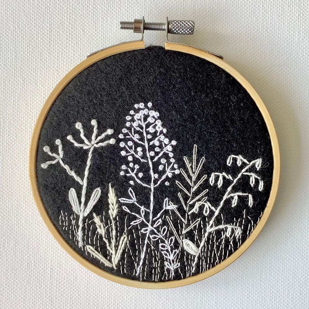 monochrome embroidery of a stylised view of wild flowers and grasses