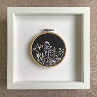 framed monochrome embroidery of a stylised view of wild flowers and grasses