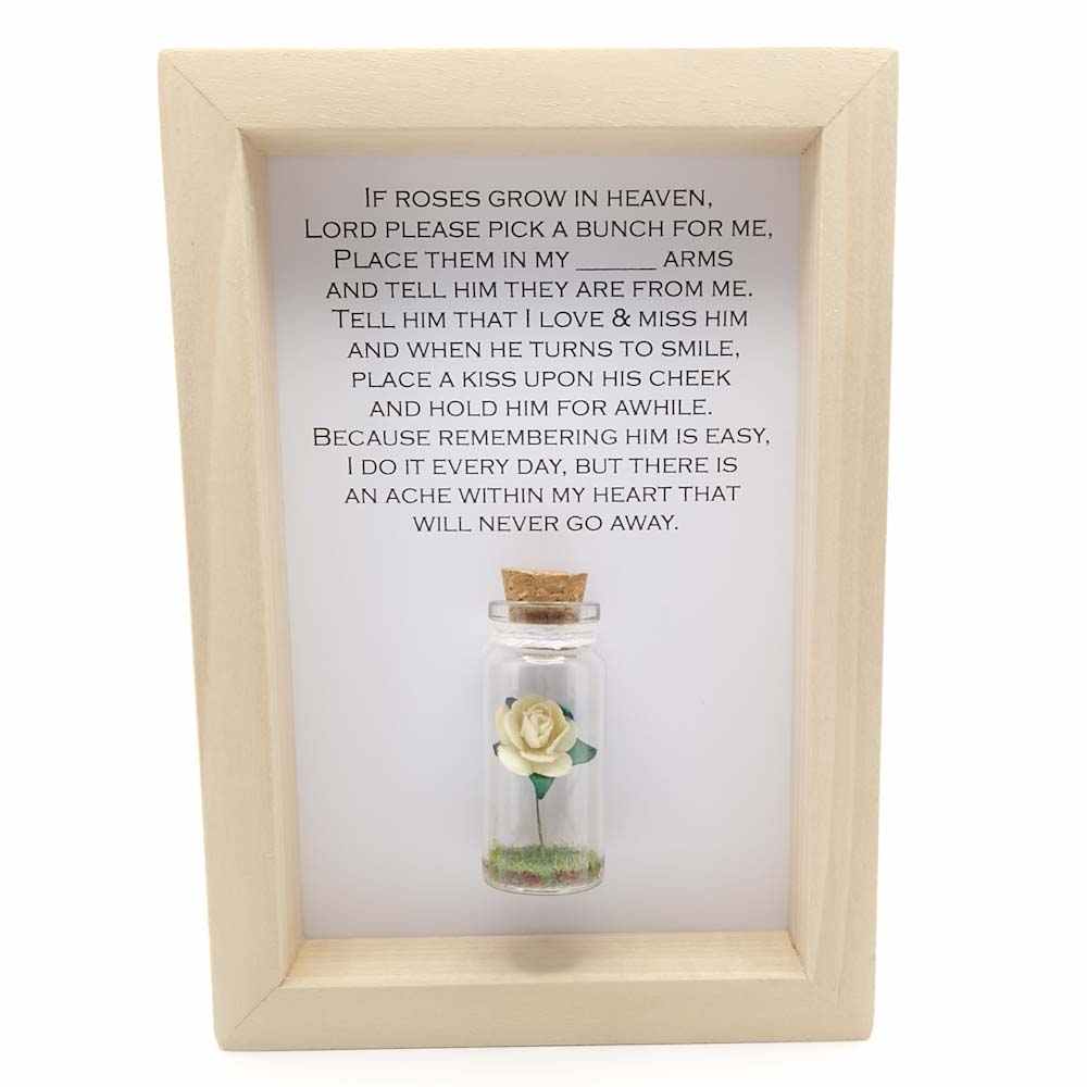 a little wood 6x4 frame with a miniature glass bottle containing a cream paper rose anda printed personalised memorial quote