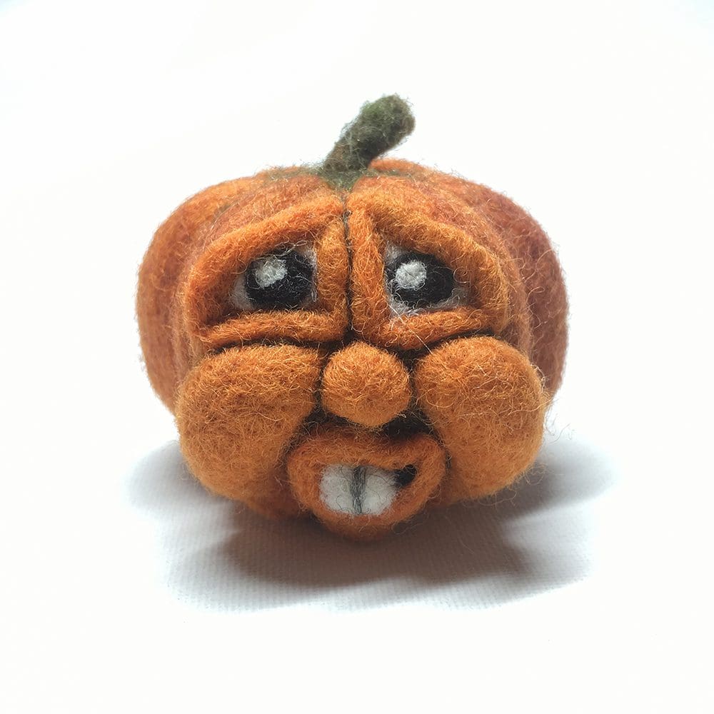 Needle felted pumpkin face with large eyes and toothy grin