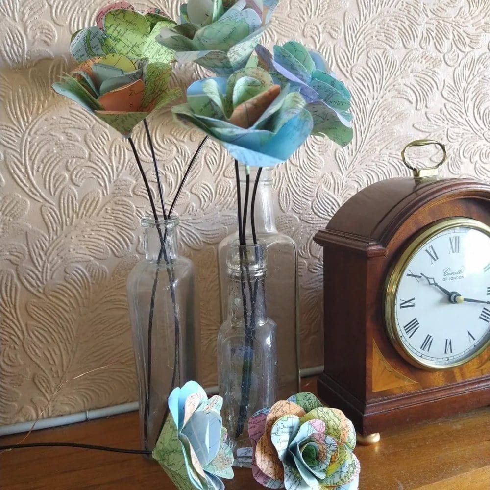 Group of map paper roses on a mantlepiece next to a clock