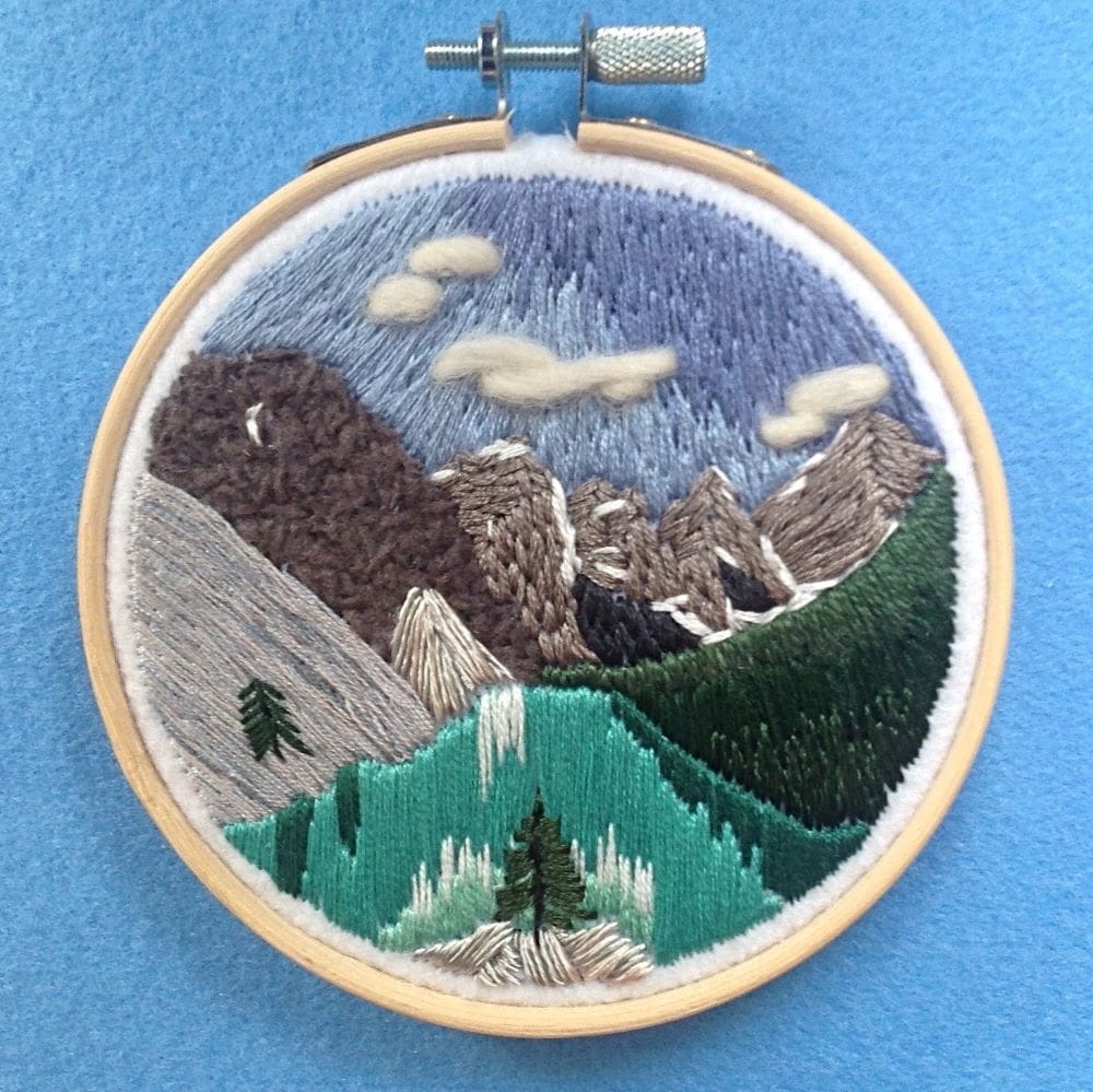 embroidered picture of a mountain lake scene