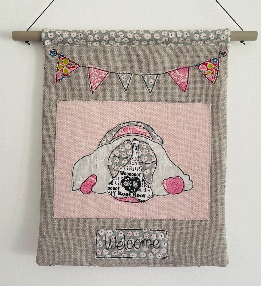 Pink textile appliqué sleeping spaniel decorative wall hanging with bunting and welcome text