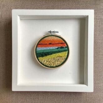 framed hand embroidered scene of the setting sun over fields