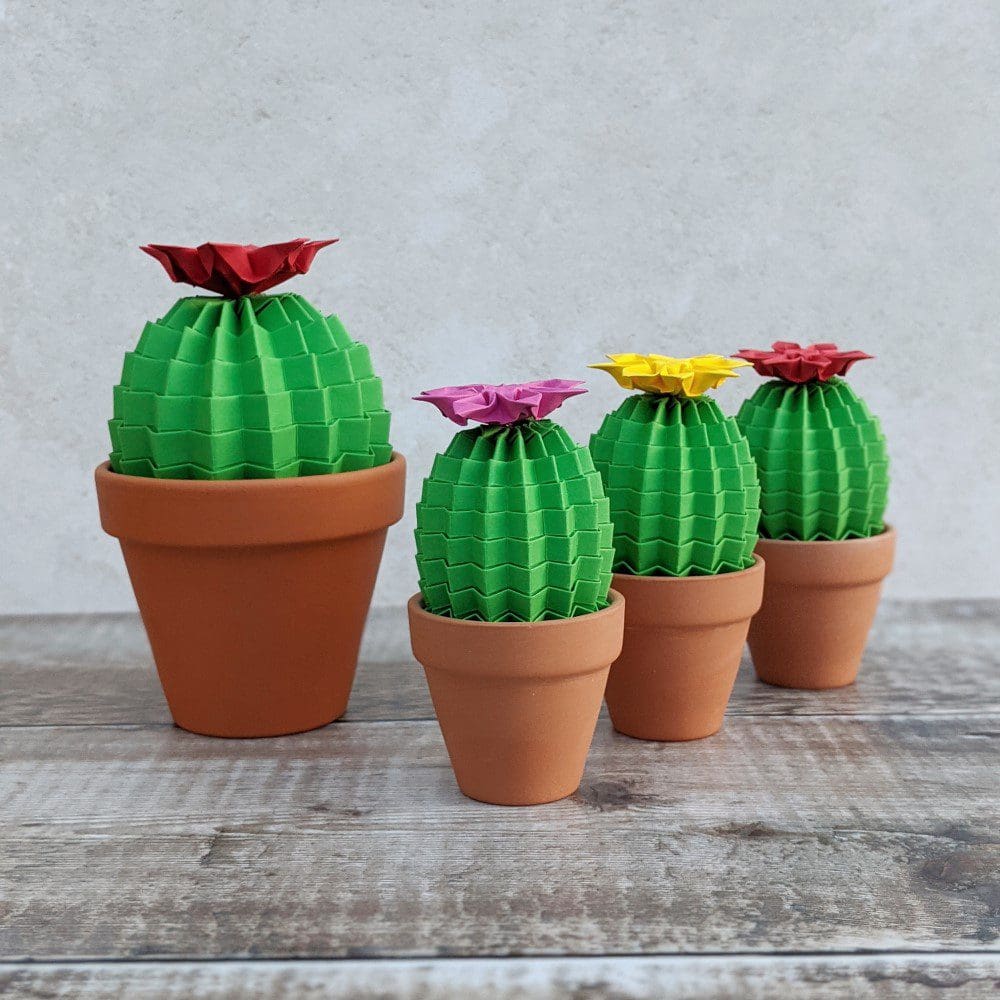 Three small green origami cacti with one large cactus