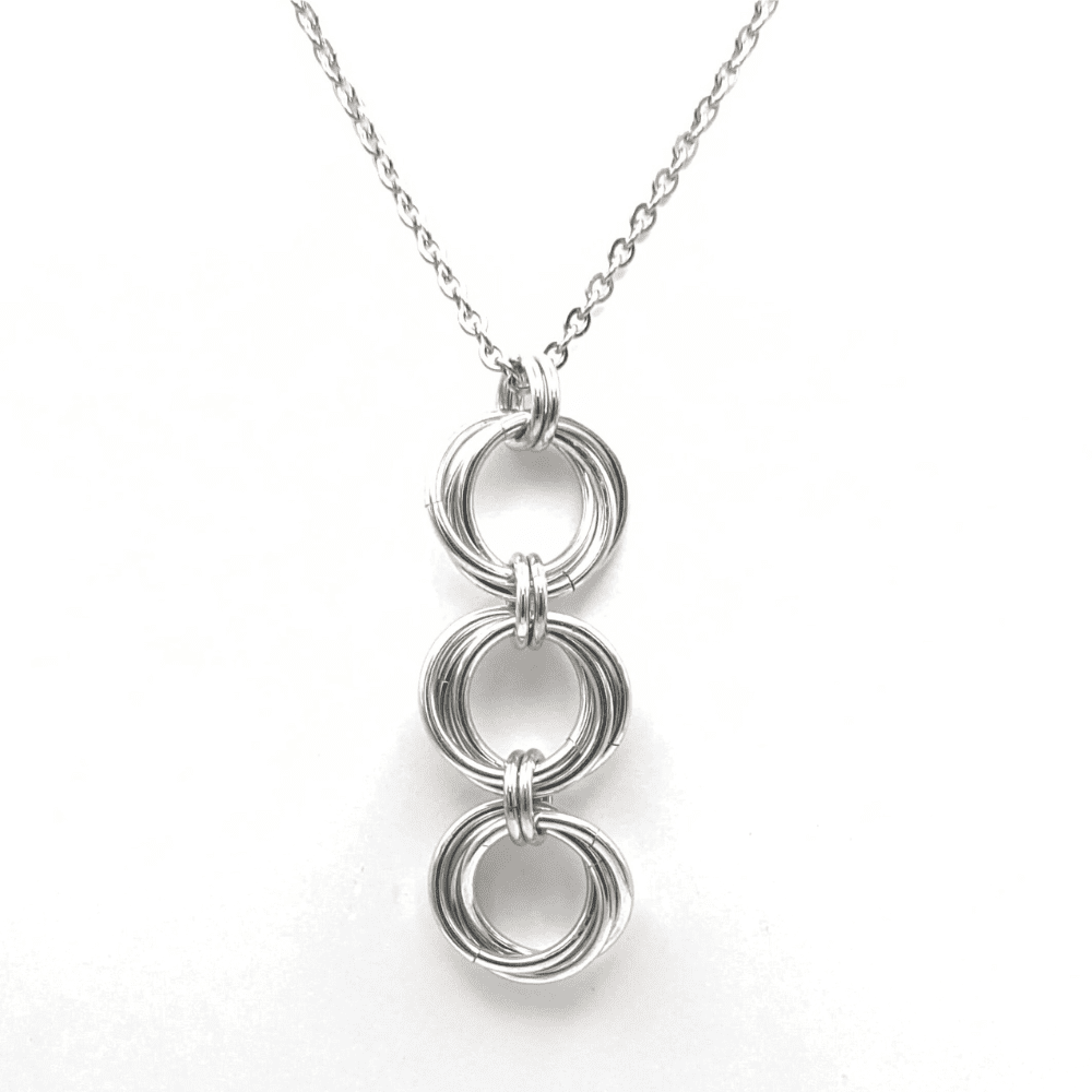 Chainmaille pendant made of three large mobius rings connected in a row which hangs from an 18" chain