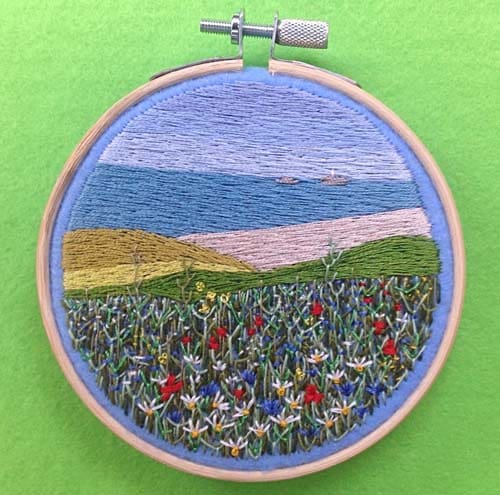 a hand embroidered scene of wild flowers over a Cornish headland