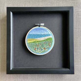 framed hand embroidered scene of wild flowers over a Cornish headland
