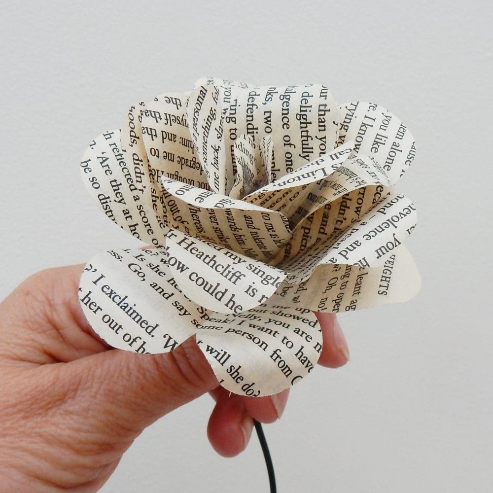 Hand holding rose made from pages from Wuthering Heights. Cream and black colour