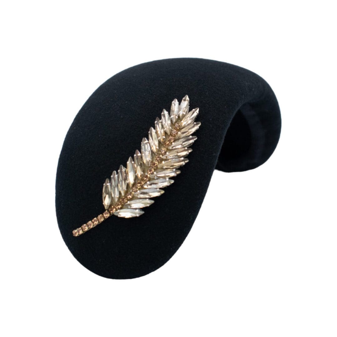 Black felt headband style hat with gold diamante feather trim on white background