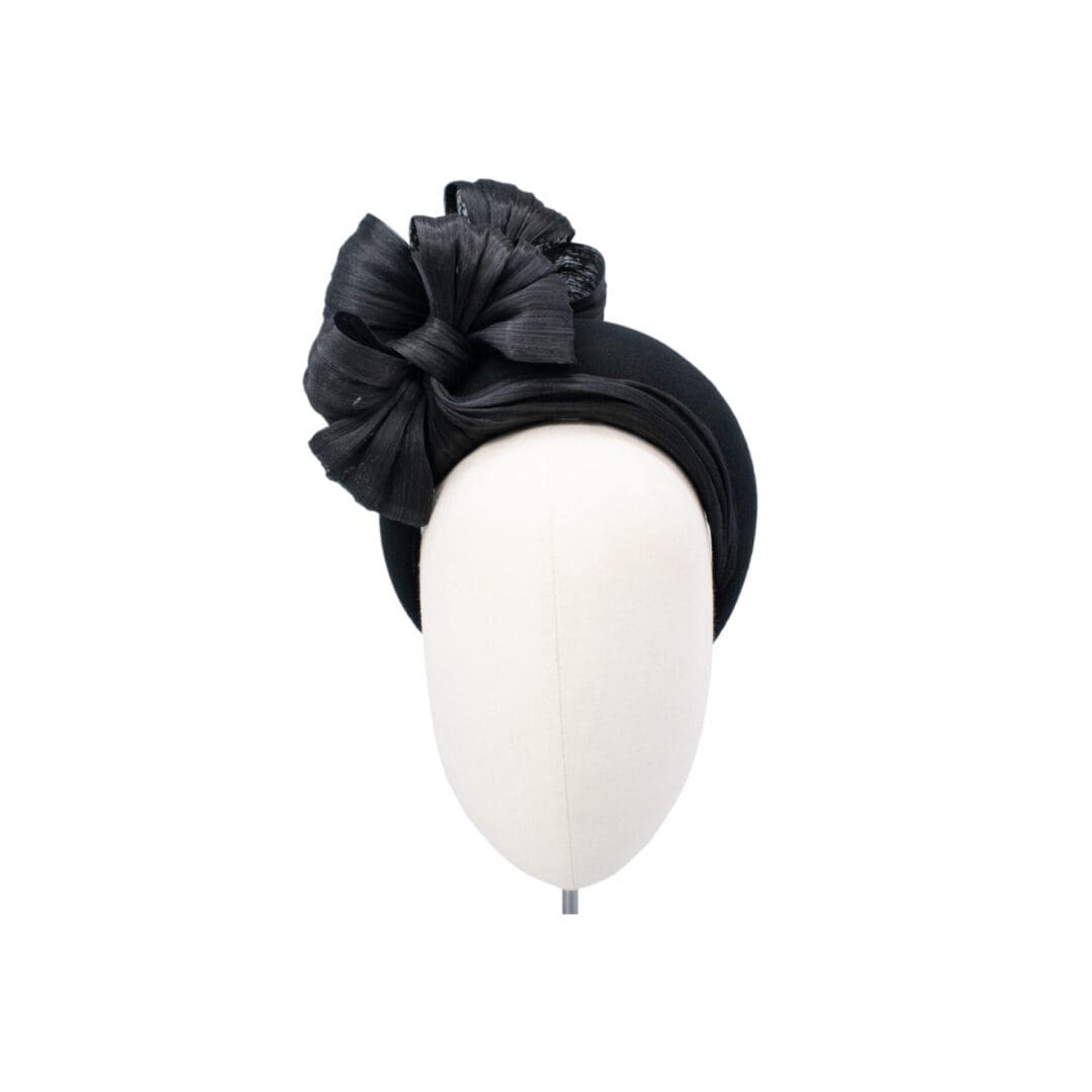 black halo headband hat with large bow trim worn on mannequin head on white background