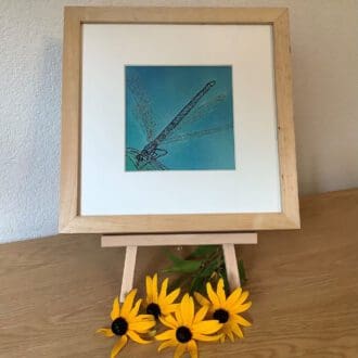 framed embroidery of a dragonfly on a blue background