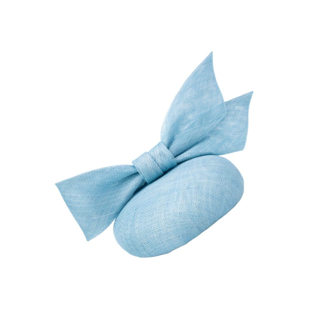 Light blue sinamay button cocktail hat with large bow on white background