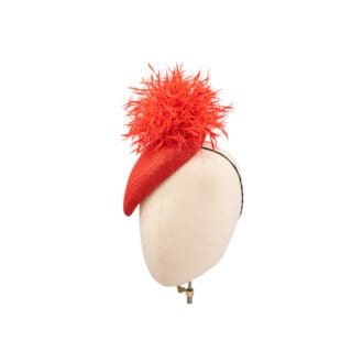 red teardrop shaped hat with feather ball worn on mannequin head