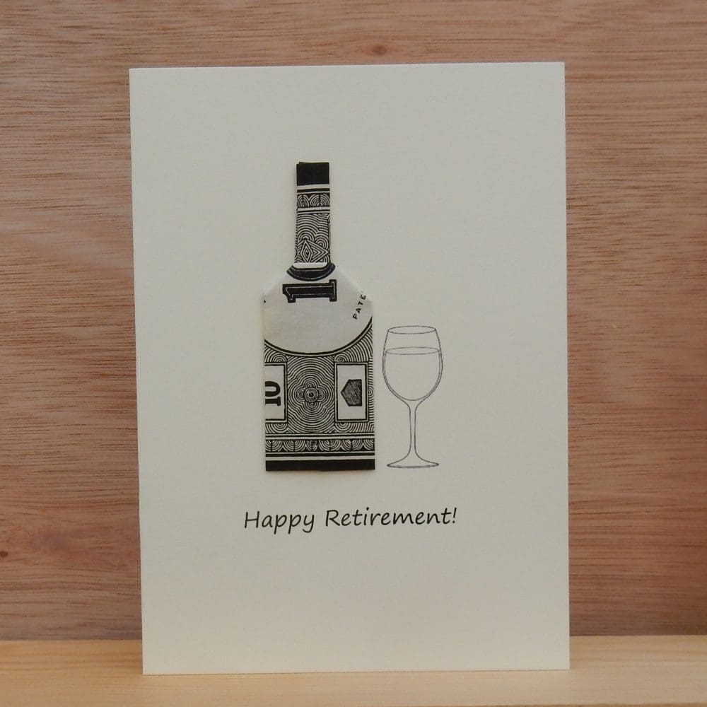 Standing cream coloured Happy Retirement card showing a bottle shape made using a piece of monopoly money. Also showing a wine glass. Bottle is black and white.
