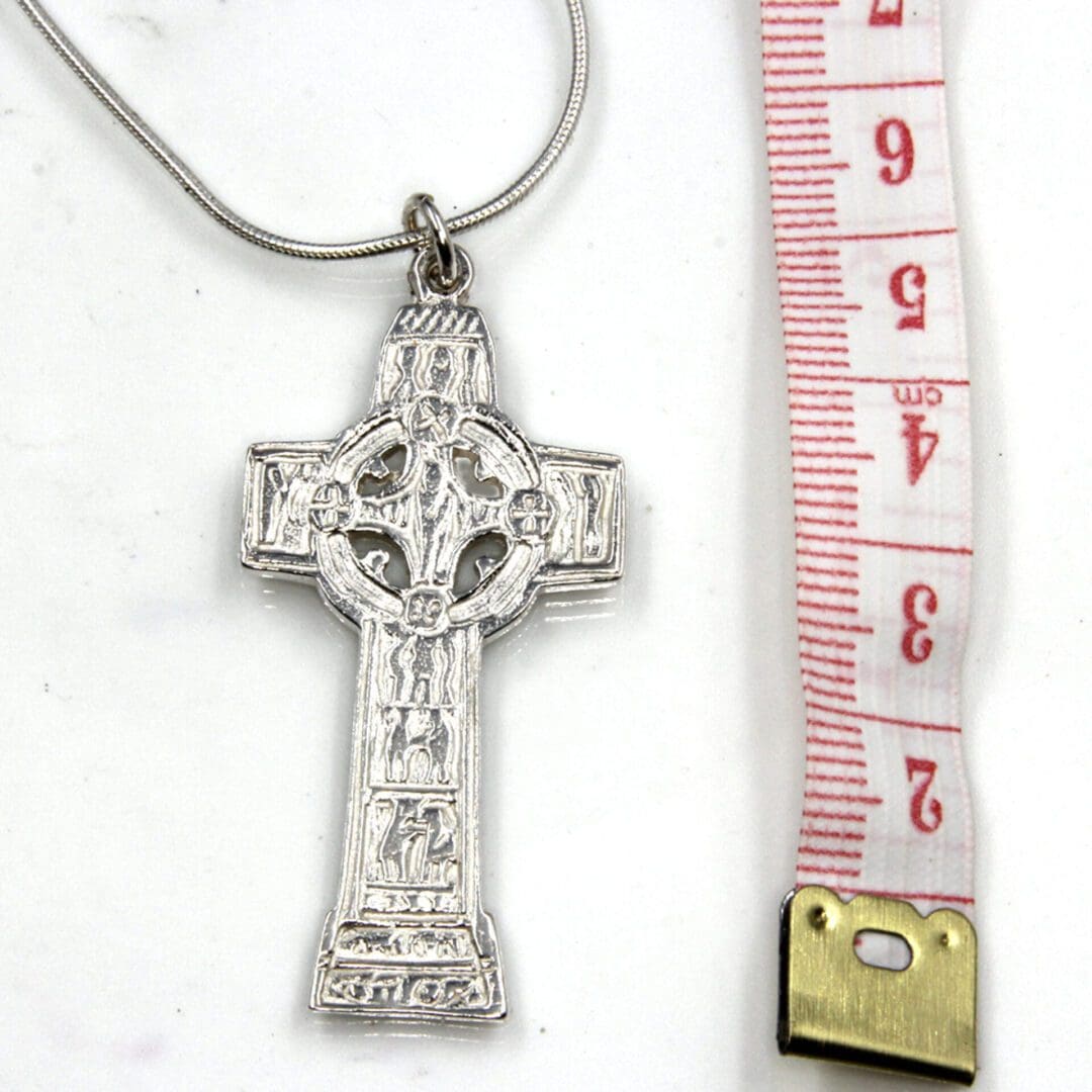 Monasterboice cross ona sname chain beaside a tape measure showing its height is approximately 5 cm.