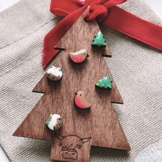 christmas themed earrings on a wooden christmas tree decoration