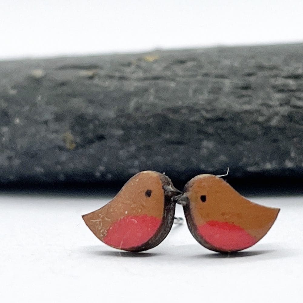 Handpainted wooden robin earrings on a white background next to a grey slate stone
