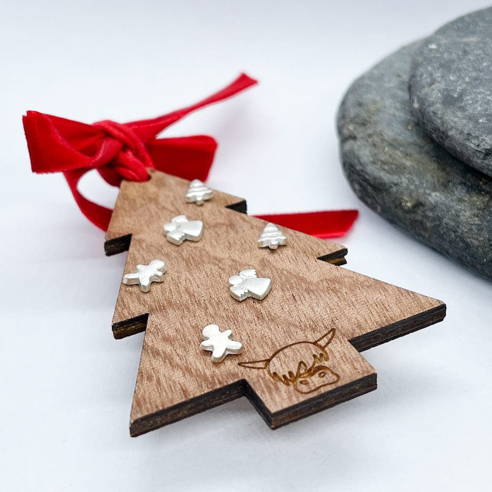 collection of silver christmas themed earrings on a wooden christmas tree on a white background