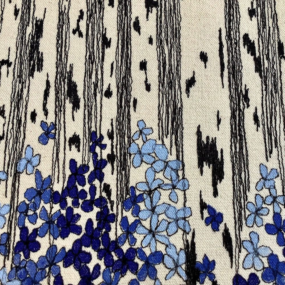 Detail of embroidered birch trees with blue woodland flowers
