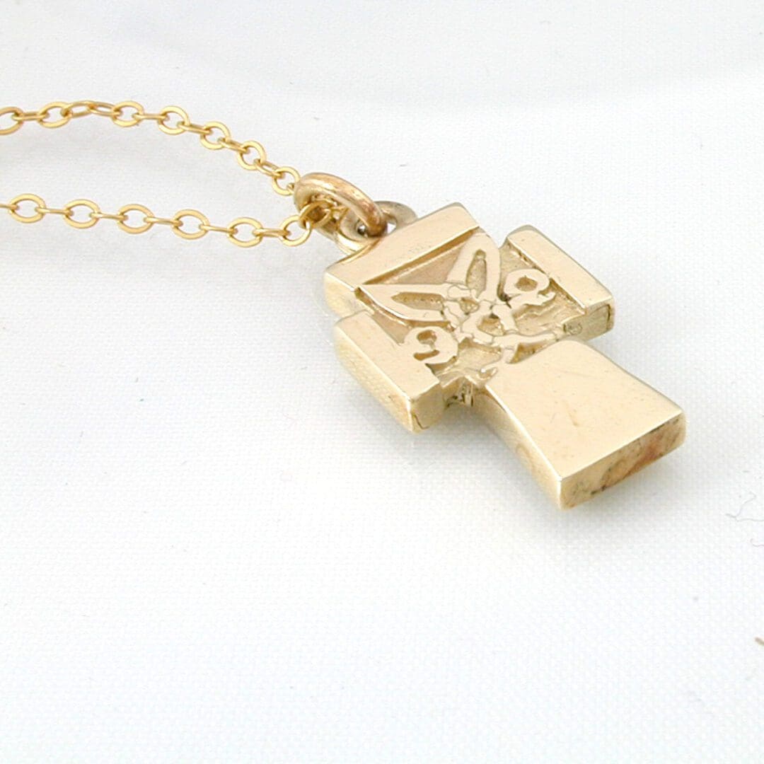small cross with a Celtic design at its centre, in yellow gold.