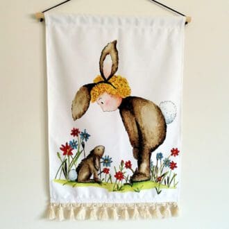 Large wall hanging in heavy duty soft cotton featuring a toddler, Lulu dressed as a brown fluffy rabbit interacting with her friend Bobbie rabbit