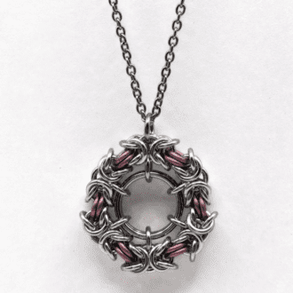 a byzantine chainmaille pendant. A circle of byzantine weave in silver and matt pastel pink rings