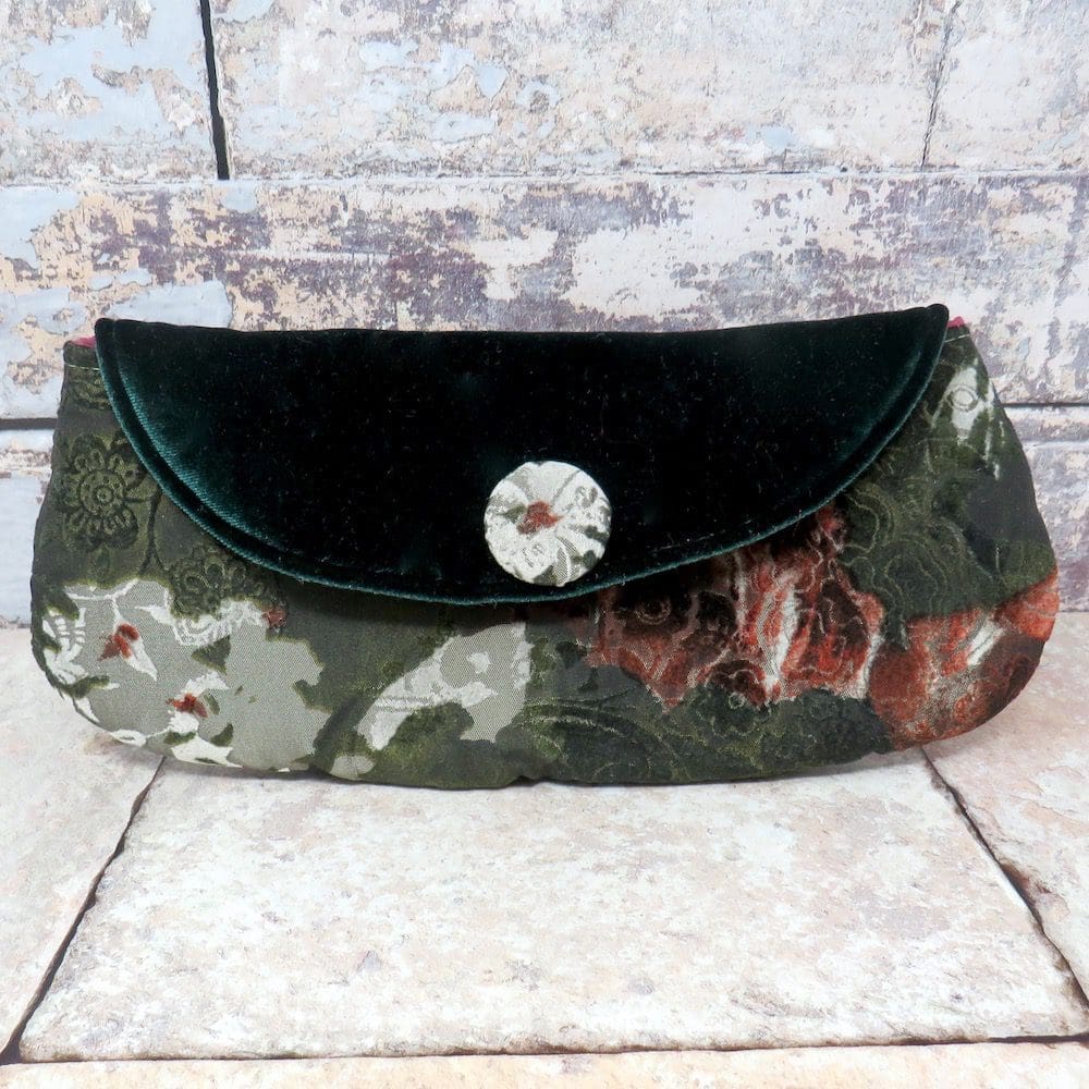 A mid sized clutch bag in a green and red flocked fabric and with a velvet flap.