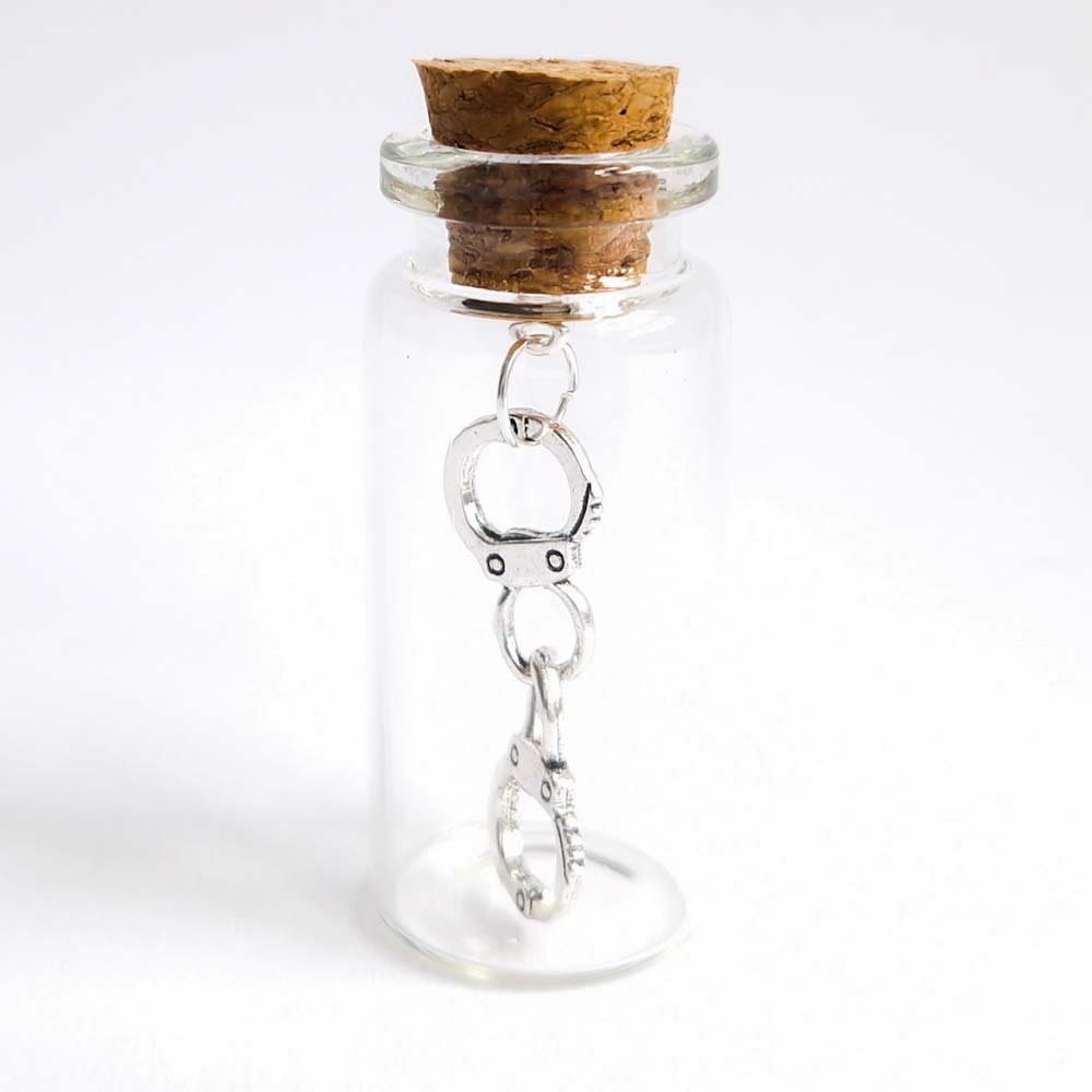 silver handcuff charm inside a miniature glass bottle