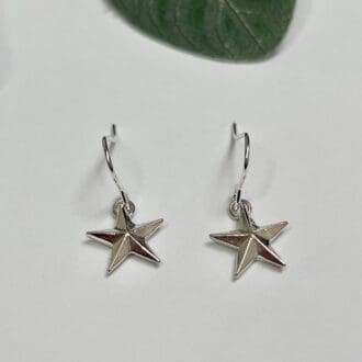 A pair of handmade solid silver star earrings. The star has a 3D effect and has been attached to a silver ear hook