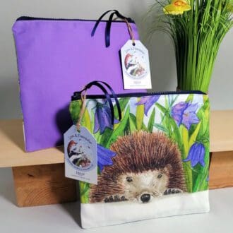 Hedgehog and harebells toiletries bag with light purple back, water resistant lining, chunky zipper fastening and internal pocket.