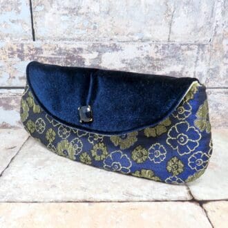 A mid sized clutch bag in a navy and gold brocade with a velvet flap. evening bag.
