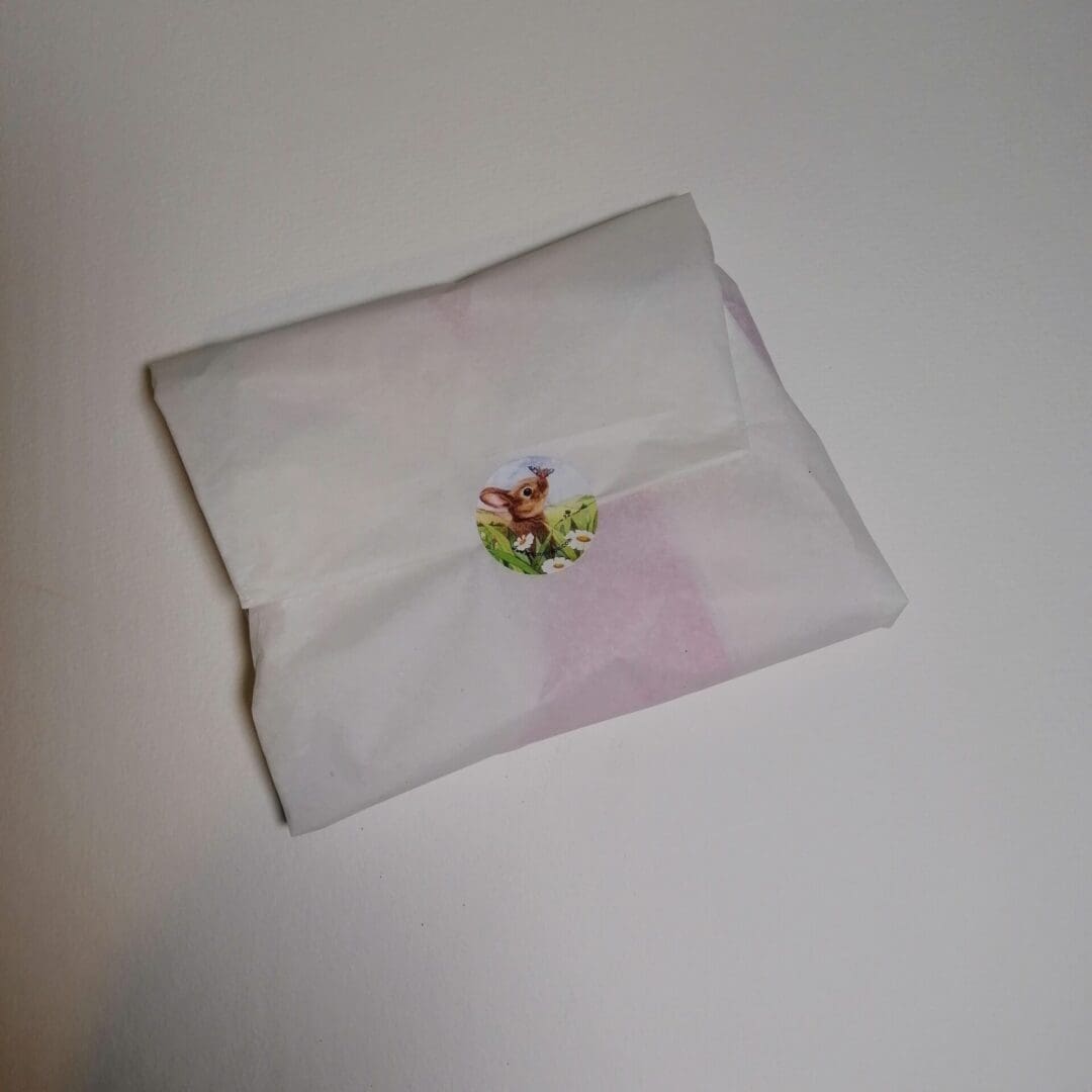 White tissue paper packaging sealed with a character sticker