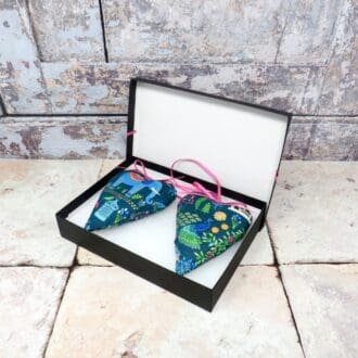 A pair of lavender scented hearts in a turquoise fabric with elephants, and presented in a black gift box.