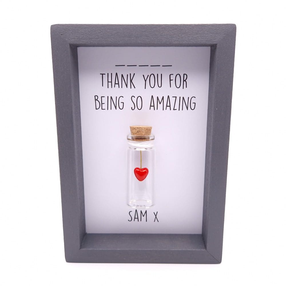 Grey frame with a red heart inside a miniature glass bottle