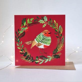 An illustrated Christmas card displayed on a white background with white fairy lights around it. The card features a robin in a green jumper, in the middle of a wreath, on a red background.