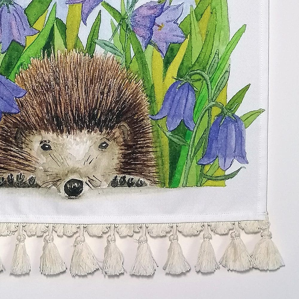 Close up detail of the hedgehog and harebells wall hanging - printed on heavyweight cotton fabric and a matching off white cotton tassel. Original illustration created as a watercolour painting.