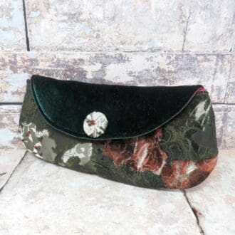 A mid sized clutch bag in a green and red flocked fabric and with a velvet flap.