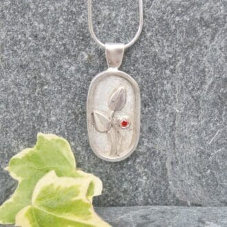 Silver shadow box pendant with a little red flower.