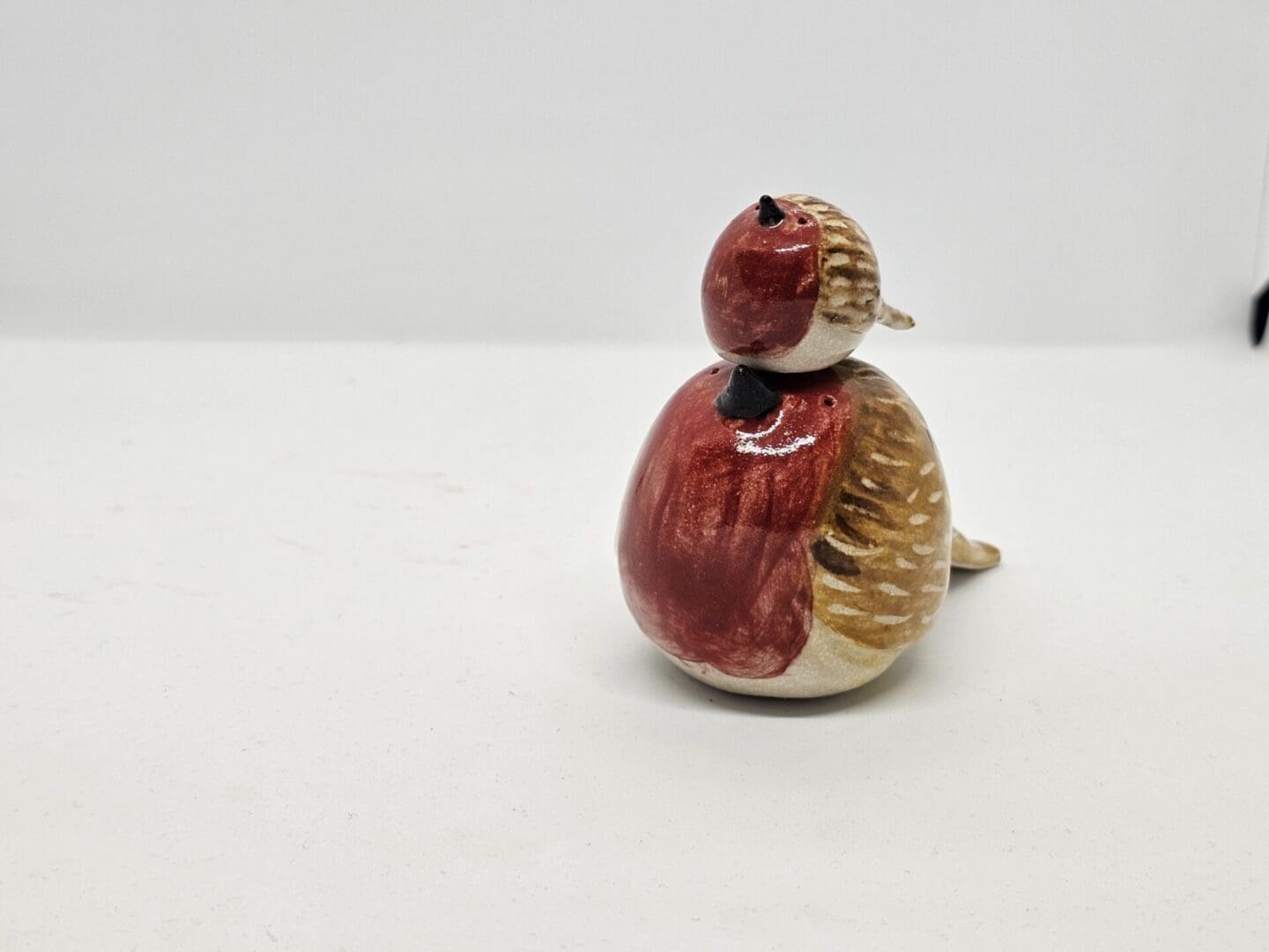 Tiny ceramic robin sitting on top of a large robin's head