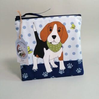 Medium sized flat cotton toiletries bag with water resistant lining and an internal pocket. Seal with a chunky zipper fastening. Beagle puppy wearing a green bandana illustration on the front face with a spotty background and paw print base.