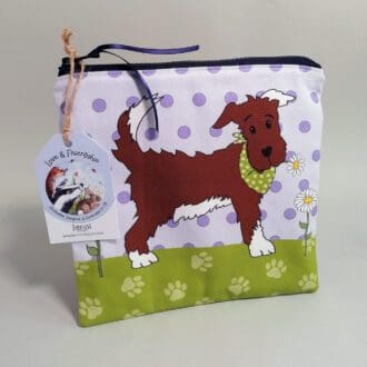 Flat, cotton medium toiletries bag featuring a sweet little dog in his best bandana. Various shades of purple spotty background, green paw print base and a pale purple back.