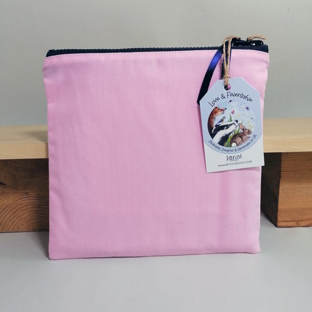 Pale pink reverse side of the cotton medium, flat toiletries bag featuring two dogs in bandanas. Sealed with a chunky zipper fastening and satin ribbon zipper pull.