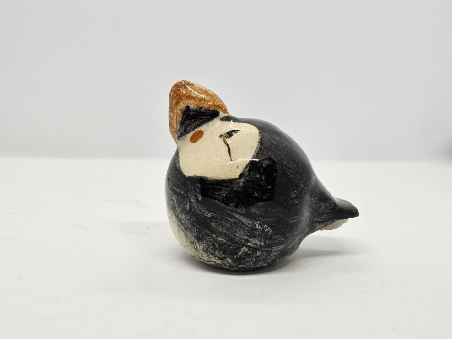 On a white background, a left facing view of a ceramic puffin