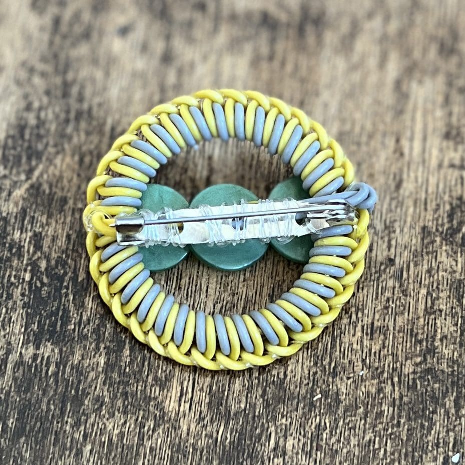 Photo shows the back view of a coloured wire brooch, displaying the silver coloured brooch pin fastener.